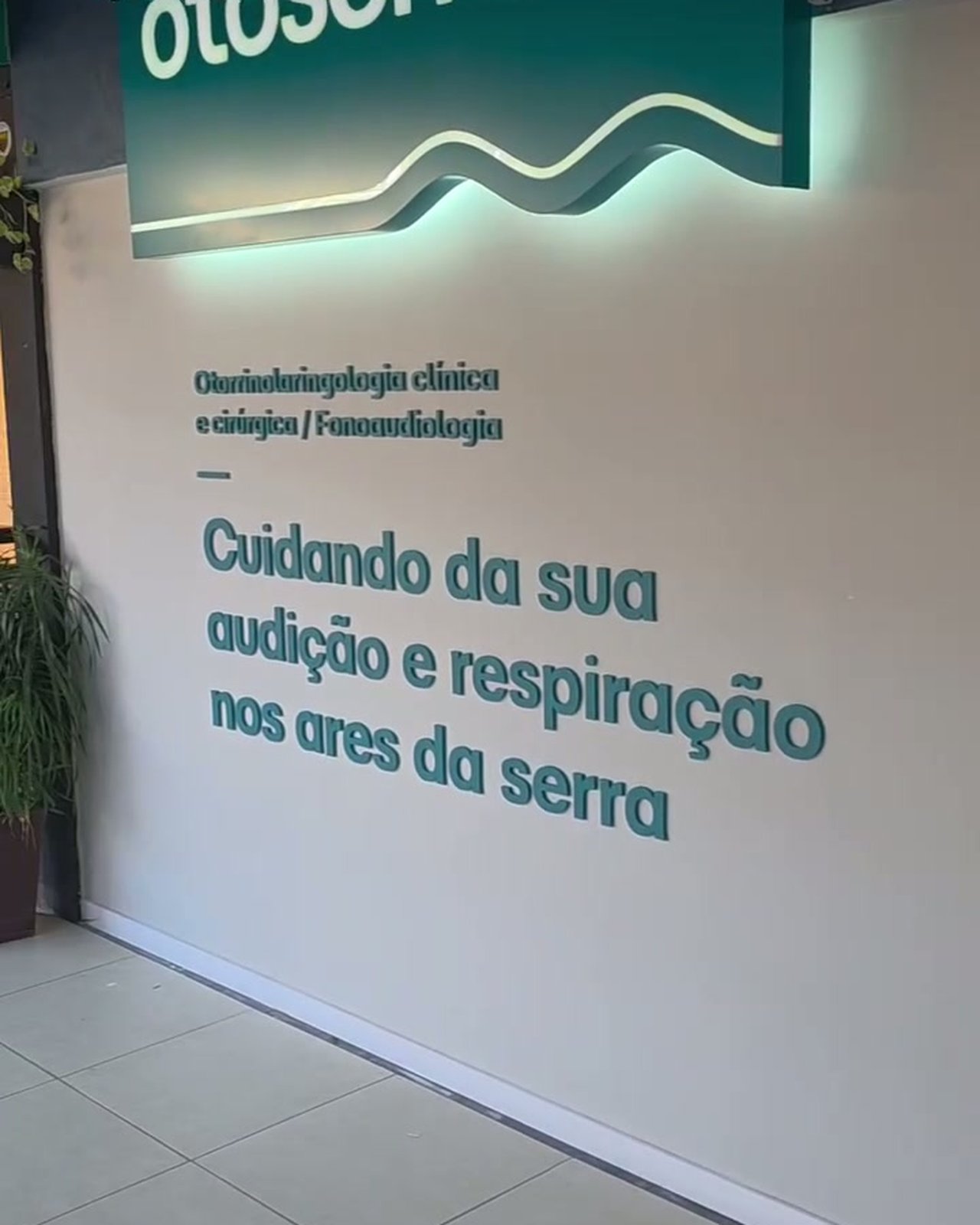 Parede da recepção com a frase 'Cuidando da sua audição e respiração nos ares da serra'